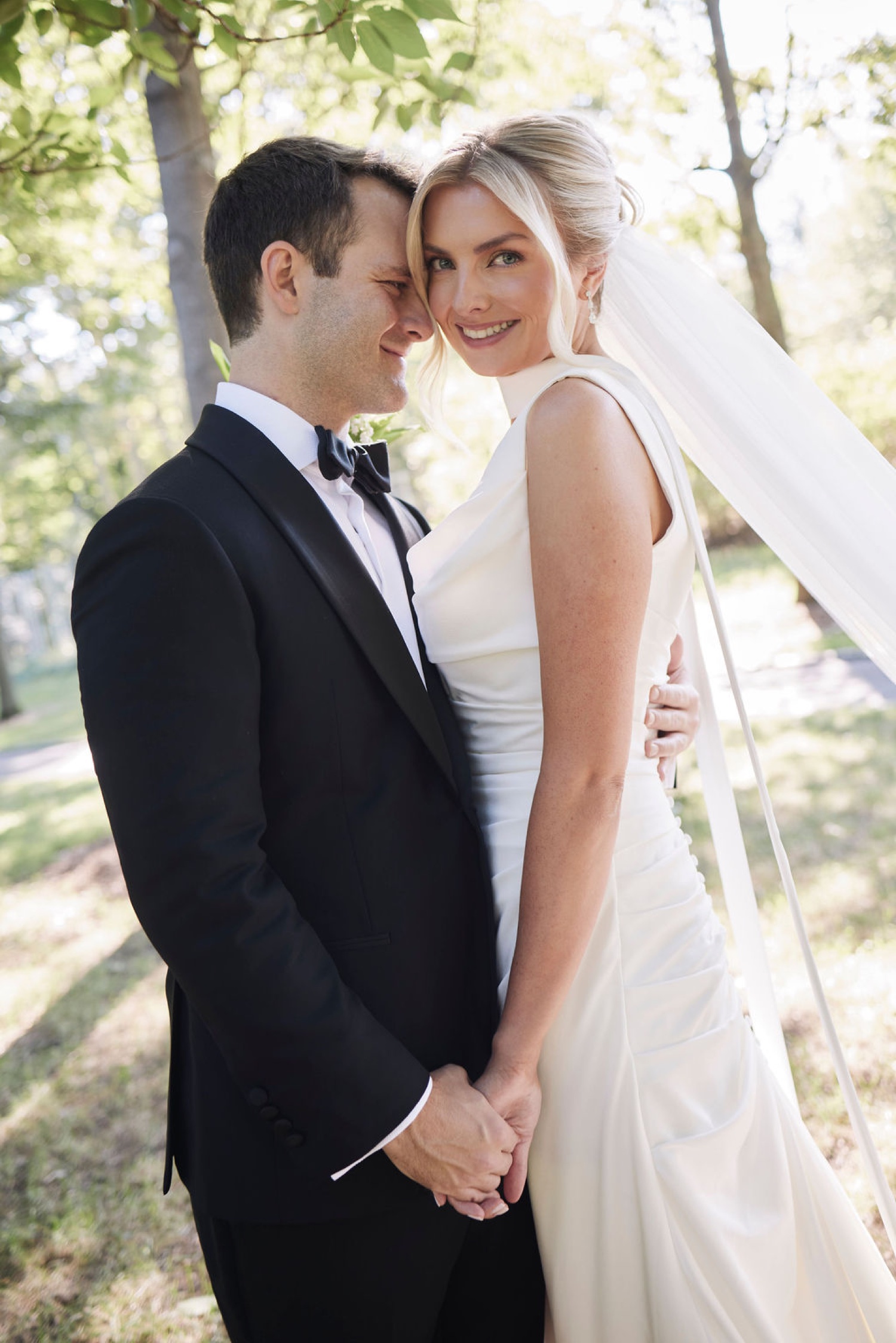 Bride and groom walking hand in hand through a golden-hour meadow